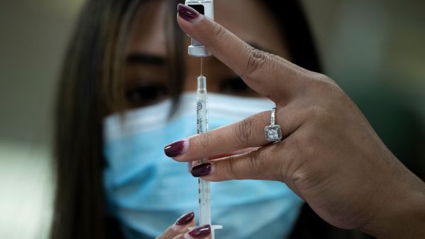 A pharmacist dilutes the Pfizer COVID-19 vaccine while preparing it to administer to staff and residents at the Goodwin House Bailey's Crossroads, a senior living community in Falls Church, Virginia, on December 30, 2020. Brendan Smialowski / AFP