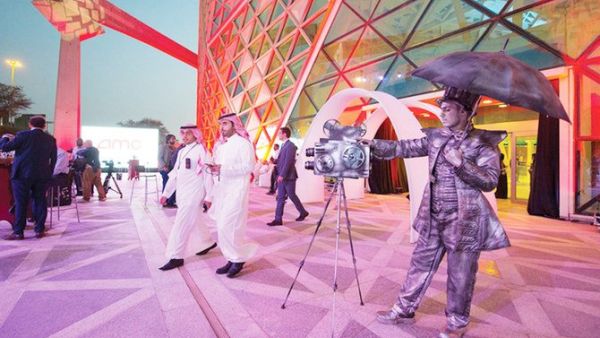 A handout picture provided by the Saudi Royal Palace on April 18, 2018, shows a mime actor standing behind a model vintage cinema camera at the entrance of the AMC cinema in the capital Riyadh ahead of the first test film screening in over three decades. AFP