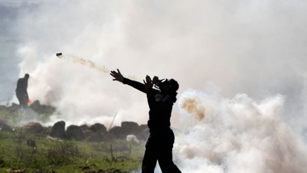 A Palestinian protester returns a tear gas canister amid clashes with Israeli security following a demonstration against the expansion of settlements near the village of Beit Dajan, east of Nablus, in the occupied West Bank, on December 25, 2020. JAAFAR ASHTIYEH / AFP