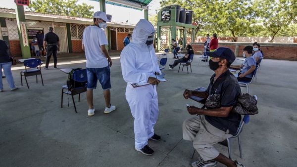A health worker interviews a Venezuelan man in Cucuta, on the Colombian border with Venezuela, as he waits to get a Covid-19 test at a testing center, on December 28, 2020. Colombia has been one of the worst hit countries in Latin America by the pandemic with more than 1.5 million cases and over 40,000 deaths. Schneyder MENDOZA / AFP
