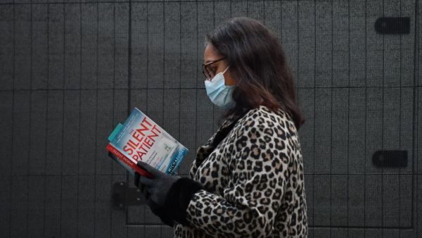 A woman reads a copy of the Silent Patient by author Alex Michaelides as she queues at an NHS Covid-19 vaccination centre for the Pfizer-BioNTech Covid-19 vaccine in London on December 30, 2020 as cases of the virus continue to soar and the Government raises restrictions around the country. Britain on December 30 became the first country in the world to approve AstraZeneca and Oxford University's low-cost Covid vaccine, raising hopes it will help tackle surging cases and ease pressure on creaking health ser