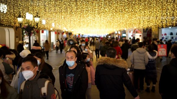 People wearing face masks walk along a shopping centre in Wuhan, in China’s central Hubei province on January 1, 2021. Noel Celis / AFP