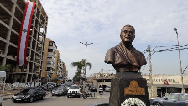 A photo taken on January 5, 2021 shows a Lebanese flag hanging on a building under construction behind the newly unveiled statue of Iran's most revered military commander, Qasem Soleimani, in the predominantly-Shiite Muslim Beirut southern suburb of Ghobeiry. Soleimani -- whom the US blamed for attacks on its interests in Iraq and elsewhere -- was killed in a US drone strike at Baghdad airport on January 3 last year, ratcheting up tensions between decades-old arch foes the United States and Iran. JOSEPH EID