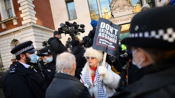 Police speak to a supporter of Wikileaks founder Julian Assange outside Westminster Magistrates court in London as he appears for a bail hearing on January 6, 2021. JUSTIN TALLIS / AFP