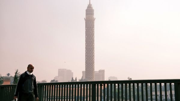 A man walks along the side of the October 6 bridge connecting Egypt's twin districts of Cairo and Giza, over the capital's Nile island of Zamalek on January 6, 2021, while the landmark Cairo Tower is seen in the background. Coptic Christians in Egypt celebrate Christmas on January 7th which is a public holiday in Egypt. Amir MAKAR / AFP