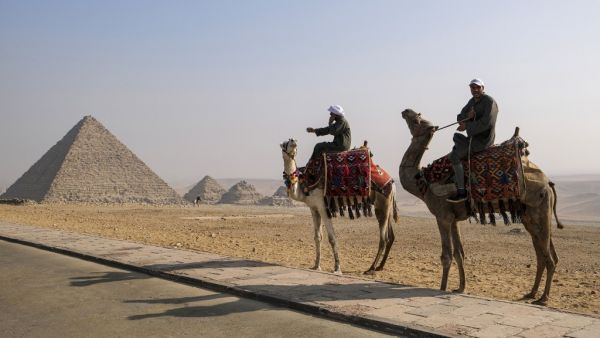 Camel trainers ride camels awaiting tourists by the Pyramid of Menkaure (Menkheres) at the Giza Pyramids Necropolis on the western outskirts of the Egyptian capital's twin city of Giza on January 7, 2021. Amir MAKAR / AFP