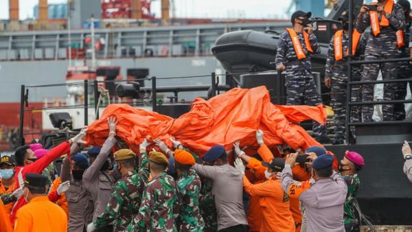 Rescue workers carry recovered debris at the port in Jakarta on January 10, 2021, during the search operation for Sriwijaya Air flight SJY182 which crashed after takeoff from Jakarta on January 9. Dany Krisnadhi / AFP