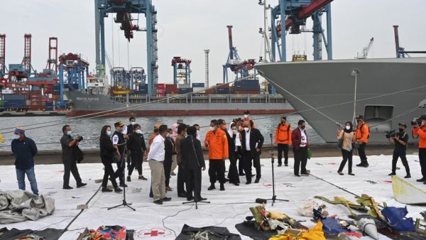 Members of the search and rescue teams and members of the Indonesian parliament look at pieces of wreckage from Sriwijaya Air flight SJ182 displayed at Tanjung Priok port, north of Jakarta, on January 11, 2021, after they were recovered during search operations off the coast for the Boeing 737-500 which crashed into the Java Sea minutes after takeoff on January 9. ADEK BERRY / AFP