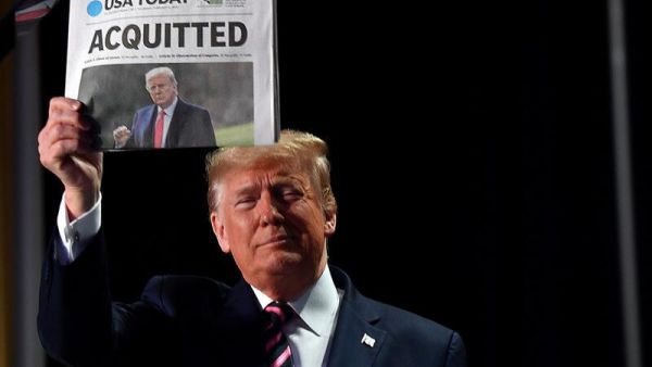 US President Donald Trump holds up a newspaper that displays a headline "Acquitted" as he arrives to speak at the 68th annual National Prayer Breakfast on February 6, 2020 in Washington,DC. President Donald Trump said Thursday that he suffered a "terrible ordeal" during his impeachment.  Nicholas Kamm / AFP