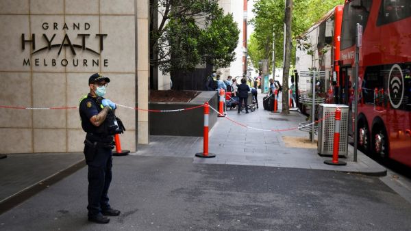 A policeman keeps watch as tennis players, coaches and officials arrive at a hotel in Melbourne on January 15, 2021, before quarantining for two weeks ahead of the Australian Open tennis tournament. William WEST / AFP