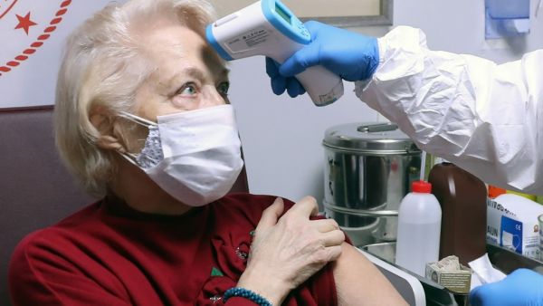 A health care worker checks the body temperature of an elderly woman at a nursing home in Ankara, on January 19, 2021, amid the Covid-19 pandemic caused by the novel coronavirus. Adem ALTAN / AFP