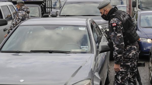 A member of the Lebanese security forces checks a citizen's documents at a COVID-19 checkpoint near the coastal town of Safra on the Tripoli-Beirut main highway on January 19, 2021, as Lebanon enters a second week under lockdown aimed at preventing the country's creaking healthcare system from collapsing. JOSEPH EID / AFP