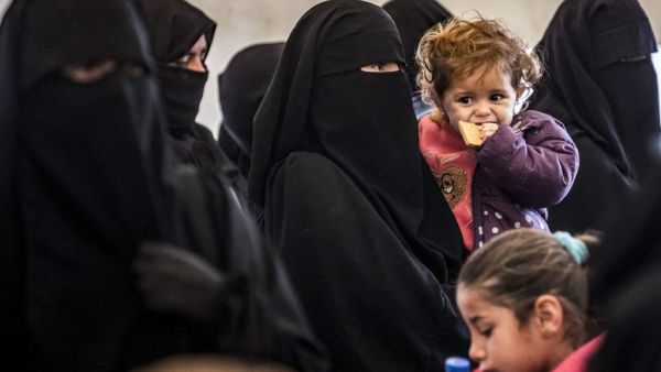 A veiled woman stands carrying a child alongside others during the release of persons suspected of being related to Islamic State (IS) group fighters from the Kurdish-run al-Hol camp in Hasakeh governorate in northeastern Syria, on January 19, 2021. Delil SOULEIMAN / AFP