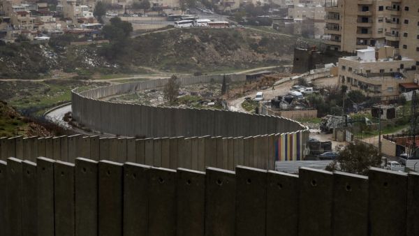 A picture taken on January 20, 2021 shows the Israeli settlement of Pisgat Zeev (L), built in a suburb of the mostly Arab east Jerusalem, and the Palestinian Shuafat refugee camp (R) behind Israel's controversial separation wall. AHMAD GHARABLI / AFP