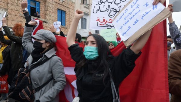 Tunisian protesters lift placards and national flags during an anti-government demonstration in the capital Tunis, on January 23, 2021. Tunisia braced for further protests after hundreds were arrested in four nights of street clashes between riot police and disaffected youths in cities across the North African country. FETHI BELAID / AFP