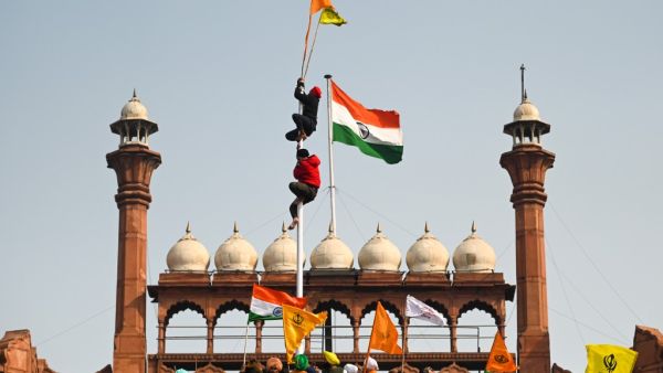 Protesters climb a flagpole at the ramparts of the Red Fort as farmers continue to demonstrate against the central government's recent agricultural reforms in New Delhi on January 26, 2021. Sajjad HUSSAIN / AFP
