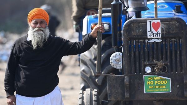 A farmer stands next to his tractor as they continue to protest against the central government's recent agricultural reforms at the Delhi-Haryana state border in Singhu on January 27, 2021. Money SHARMA / AFP