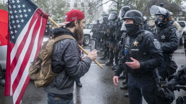 A supporter of President Trump speaks with riot police during a protest on January 6, 2021 in Salem, Oregon. Trump supporters gathered at state capitals across the country to protest today's ratification of Joe Biden's Electoral College victory over President Trump in the 2020 election. Nathan Howard/Getty Images/AFP