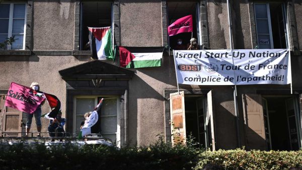 Boycott, Divestment, Sanctions (BDS) movement activists display Palestinian flags and a banner reading "Israel Start-Up Nation, Tour de France is the accomplice of the apartheid" as the pack rides during the 13th stage of the 107th edition of the Tour de France cycling race, 191 kilometers between Chatel-Guyon and Puy Mary, on Sept. 11, 2020. Photo by MARCO BERTORELLO/AFP via Getty Images