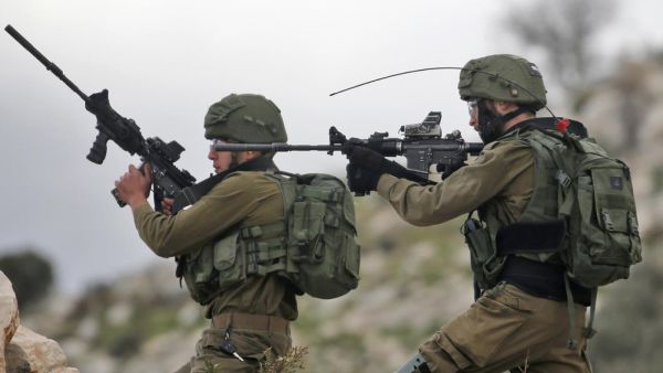 Israeli soldiers hold up their rifles towards Palestinian protesters in the village of Kfar Qaddum, near Nablus in the occupied West Bank (AFP File Photo)