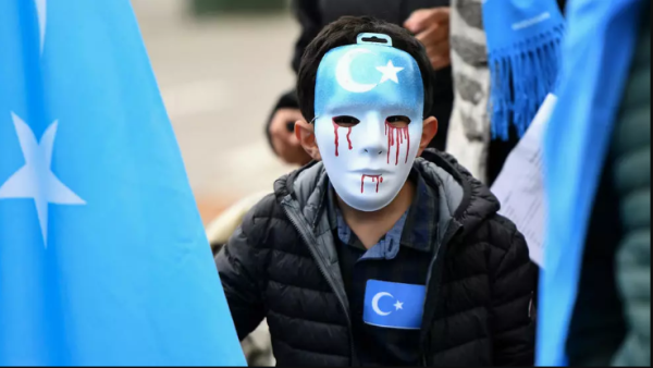 A boy wearing a blue mask with tears of blood takes part in a protest march of ethnic Uighurs, in Brussels on April 27, 2018, asking for the European Union to call upon China to respect human rights. (Emmanuel Dunand, AFP)