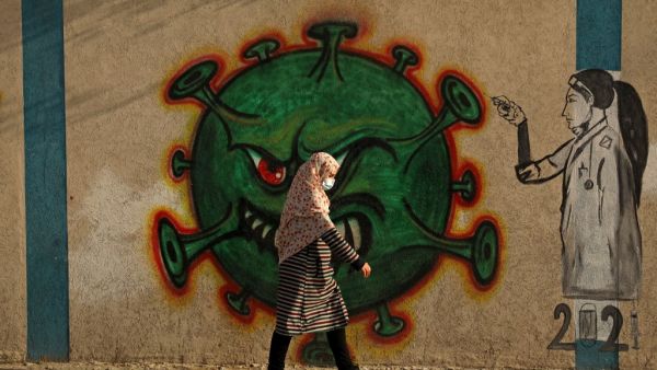 A Palestinian woman, wearing a protective mask amid the COVID-19 pandemic, walks past a coronavirus-inspired mural in Gaza City, on February 2, 2021. Mohammed ABED / AFP