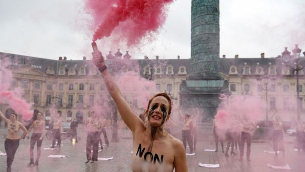 A Femen activist, with "not guilty" written on the chest, lights flares during a protest against sexism in the French judicial system at the Vendôme square in Paris on February 6, 2021. Alain JOCARD / AFP A Femen activist, with "not guilty" written on the chest, lights flares during a protest against sexism in the French judicial system at the Vendôme square in Paris on February 6, 2021. Alain JOCARD / AFP