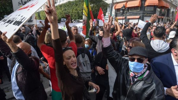 Tunisians gesture while shouting slogans against the government and police repression in the capital Tunis on February 6, 2021, as they demonstrate in commemoration of the 8th anniversary of the assassination of prominent leftist opposition leader Chokri Belaid. FETHI BELAID / AFP