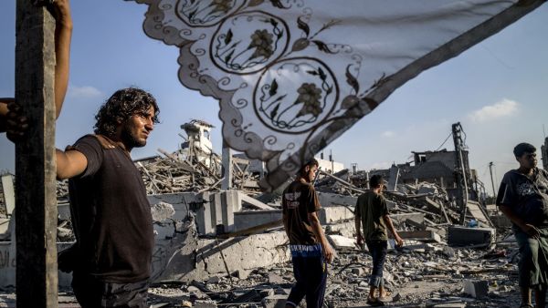 In this file photo taken on August 6, 2014 Palestinians stand next to a makeshift shelter erected outside their destroyed house in the devastated neighbourhood of Shejaiya in Gaza City. MARCO LONGARI / AFP
