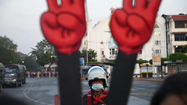 A policeman looks on next to a cut-out of the three finger salute during a demonstration against the military coup in Yangon on February 7, 2021. STR / AFP A policeman looks on next to a cut-out of the three finger salute during a demonstration against the military coup in Yangon on February 7, 2021. STR / AFP