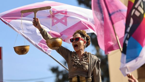 An Israeli protester dressed as Lady Justice takes part in a demonstration outside the Jerusalem district court while Prime Minister Benjamin Netanyahu attends a hearing in his corruption trial, on February 8, 2021. Israel's Prime Minister Benjamin Netanyahu returns to court to formally respond to the corruption charges against him, as his trial enters an intensified phase six weeks before he faces re-election. EMMANUEL DUNAND / AFP