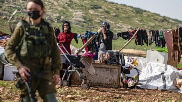 Bedouin women and children remain by their tents and structures after Israeli forces demolished them in the Humsa area east of the Palestinian village of Tubas, in the occupied West Bank, on February 8, 2021. JAAFAR ASHTIYEH / AFP