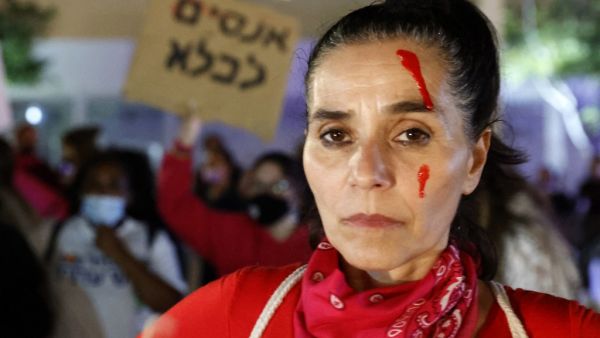 An Israeli woman with red paint on her face attends a protest in Tel Aviv against femicide, domestic violence, rape and murder cases against women in Israeli society, on February 8, 2021.  JACK GUEZ / AFP