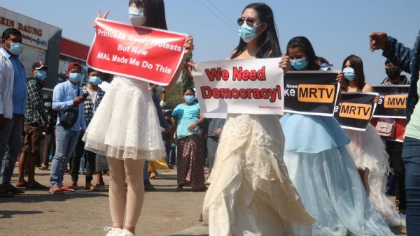 Protesters in gowns hold up signs during a demostration against the military coup in Naypyidaw on February 11, 2021. STR / AFP
