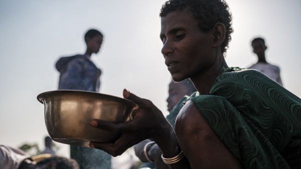 An Internally Displaced Person (IDP), fleeing from violence in the Metekel zone in Western Ethiopia, holds a bowl with food at a camp in Chagni, Ethiopia, on January 27, 2021. Inter-ethnic violence in Ethiopia's west -- concentrated in a lowland area known as Metekel -- predates a brutal three-month-old conflict farther north pitting Prime Minister Abiy Ahmed's government against the former ruling party of the Tigray region.  EDUARDO SOTERAS / AFP