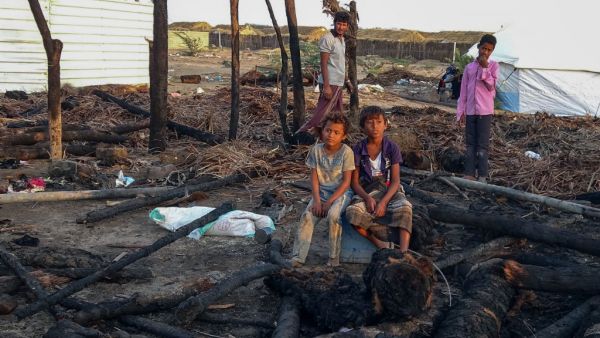 Displaced Yemeni youths sit by of calcined wooden poles after a fire broke out in a shelter in the war-ravaged western Hodeida province, on February 16, 2021. Khaled Ziad / AFP