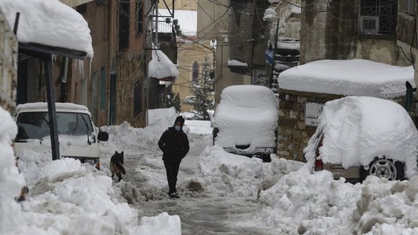 A man walks along a snow-covered street in the town of Bcharre in mount Lebanon, north of the capital Beirut, on February 19, 2021. JOSEPH EID / AFP