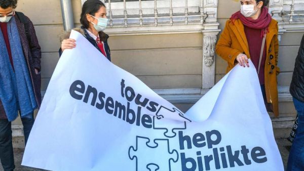 Two women hold a banner reading “All together” as Galatasaray University’s French teachers without working permits give a press conference in front of Galatasaray university in Istanbul on February 23, 2021. (AFP)