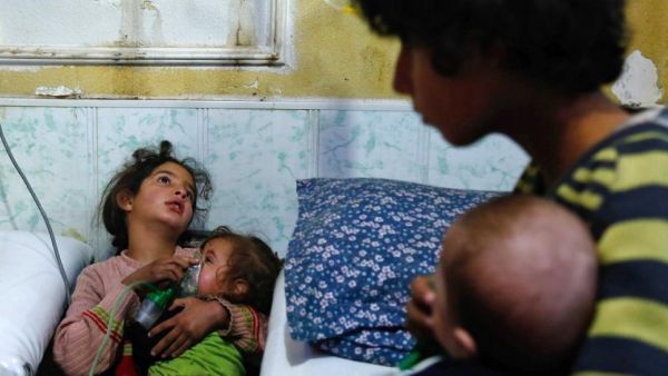 A Syrian girl holds an oxygen mask over the face of an infant at a make-shift hospital after a gas attack on Douma in the eastern Ghouta region on the outskirts of Damascus on January 22, 2018. (AFP)