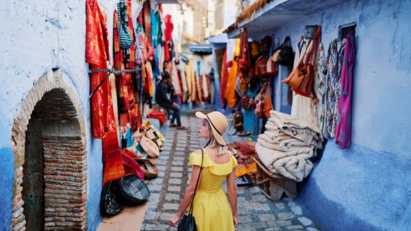 Colorful traveling by Morocco. Young woman in yellow dress walking in medina of blue city Chefchaouen  (Shutterstock)