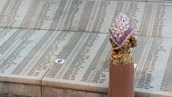 Muslim woman in front of Wall of names at Memorial center Potocari  (Shutterstock)	