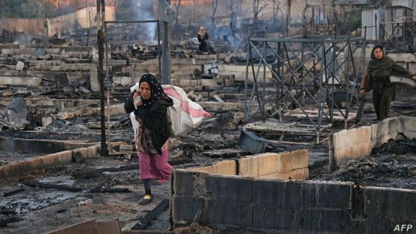 Syrian refugees salvaging her belongings from a camp set on fire!