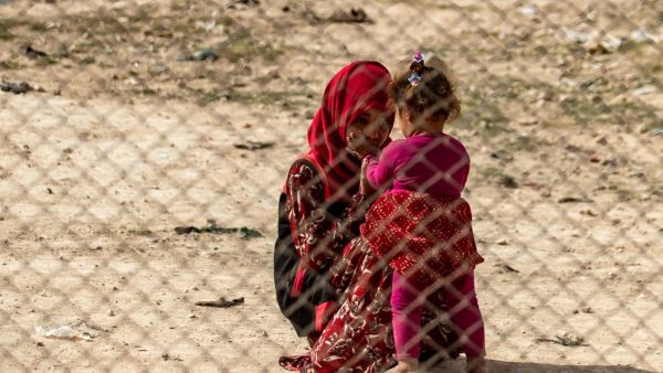 A young girl interacts with a toddler at the Kurdish-run al-Hol camp 
