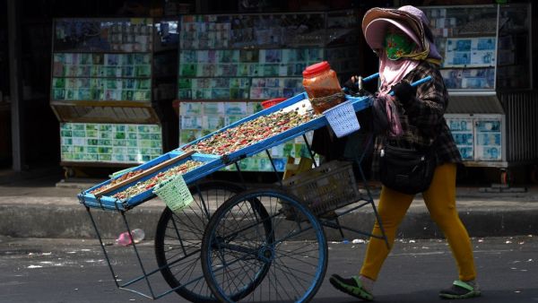 A woman selling dried river shells walks along a street 