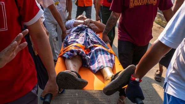 People carry an injured resident, who was shot with rubber bullets as security force destroyed barricades erected by protesters against the military coup, in Yangon on March 9, 2021. STR / AFP People carry an injured resident shot with rubber bullets