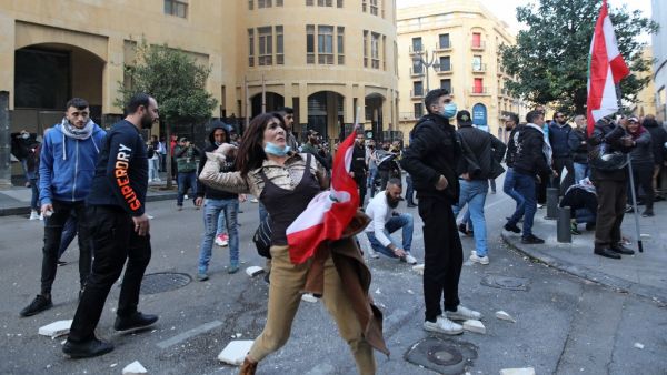 A Lebanese demonstrator hurls rocks over a fortified gate