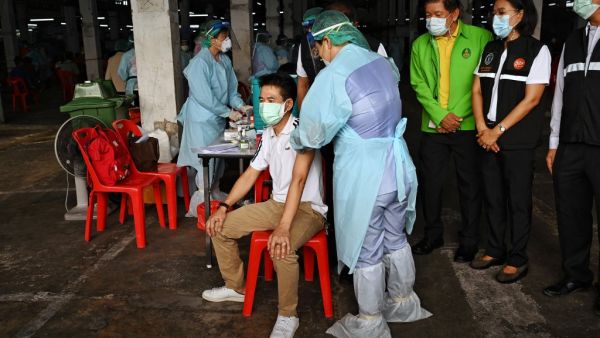 Officials watch as a man is inoculated with the CoronaVac vaccine