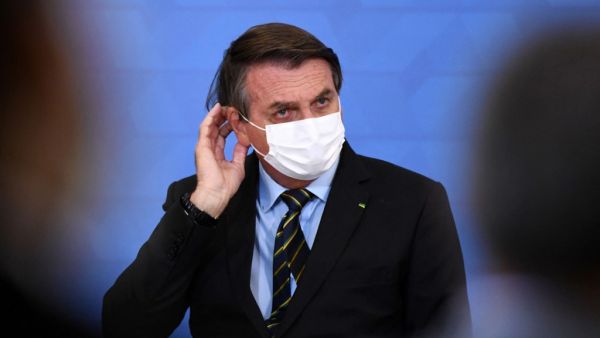 Brazilian President Jair Bolsonaro gestures as he speaks during the announcement of support measures to philanthropic hospitals in the fight against the novel coronavirus disease, COVID-19, at Planalto Palace in Brasilia, on March 25, 2021. Brazil's death toll in the coronavirus pandemic surpassed 300,000 on March 24, as a deadly surge that has pushed hospitals to the brink made it the second country after the United States to pass the bleak milestone. EVARISTO SA / AFP COVID-19 cases in Brazil spikes to 100K