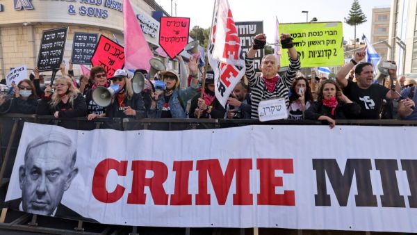 Protesters, one wearing a mask depicting Israeli Prime Minister Benjamin Netanyahu