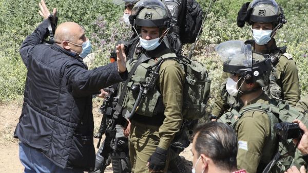 A Palestinian confronts Israeli soldiers